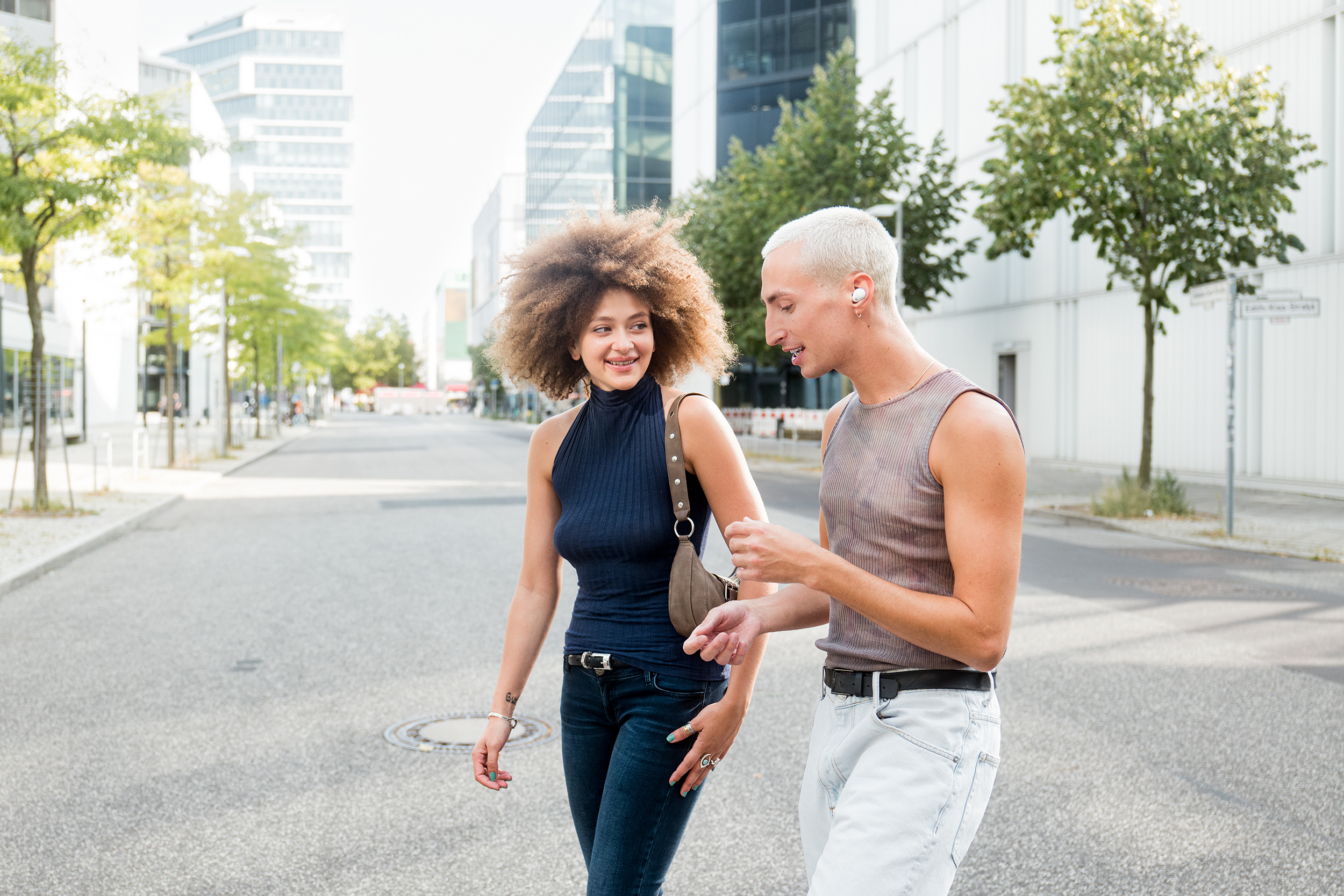 Two people in conversation outdoors; one is wearing a wired earbud